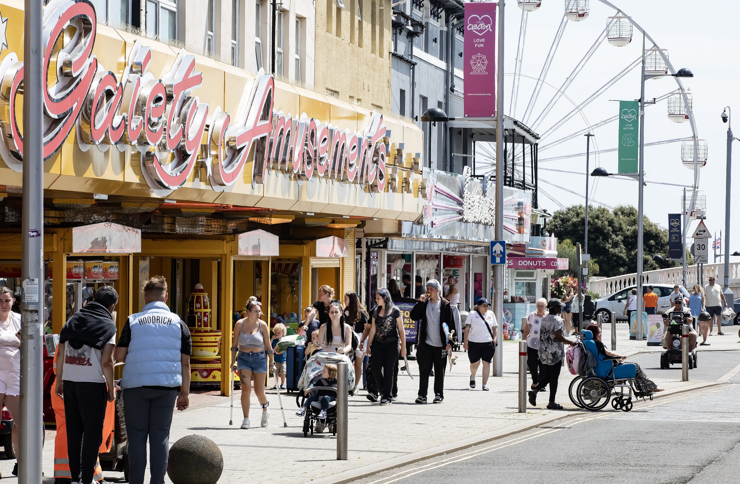View of busy street with arcades and big wheel in background